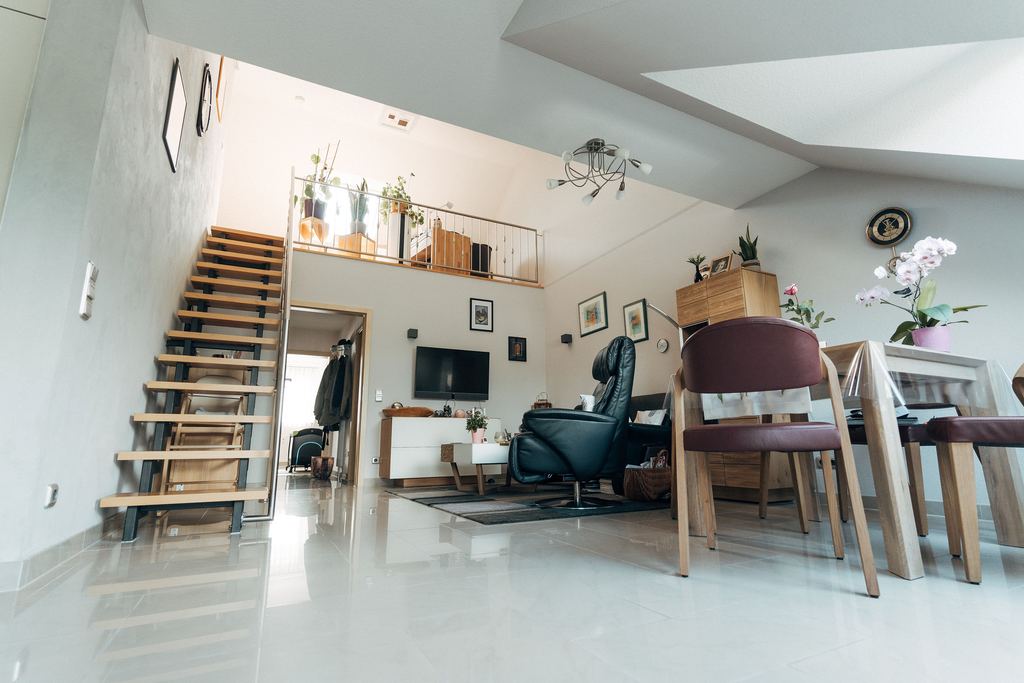 Heller Wohnbereich einer Maisonette mit offener Treppe und Galerie